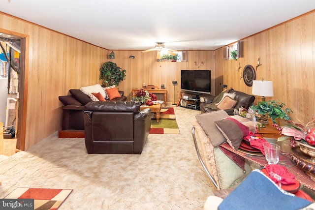 carpeted living room featuring wooden walls and a ceiling fan