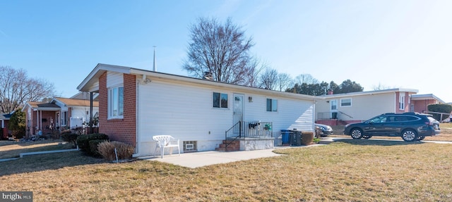 rear view of property with a yard and brick siding