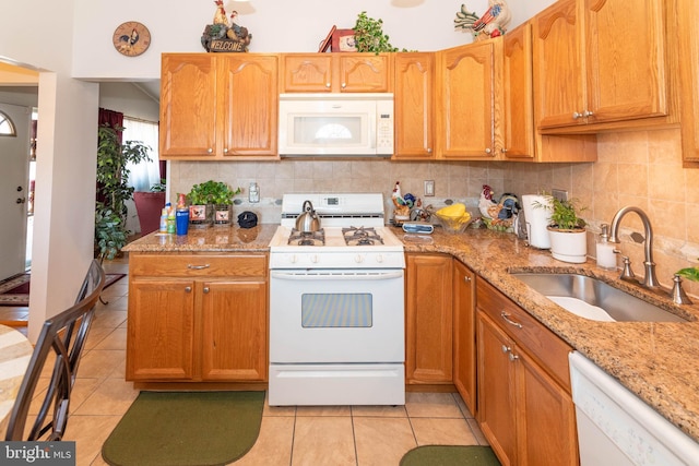 kitchen featuring a sink, backsplash, white appliances, light tile patterned floors, and light stone countertops