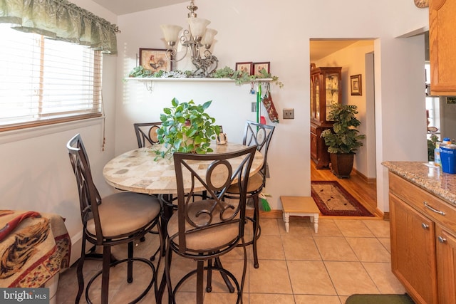 dining area with a notable chandelier, light tile patterned floors, and baseboards