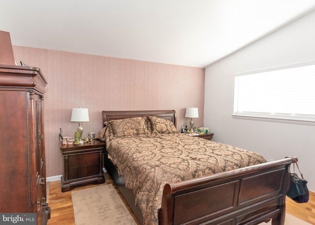 bedroom featuring vaulted ceiling, baseboards, and light wood finished floors