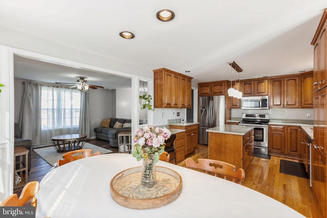 kitchen featuring light wood finished floors, brown cabinetry, appliances with stainless steel finishes, and a kitchen island