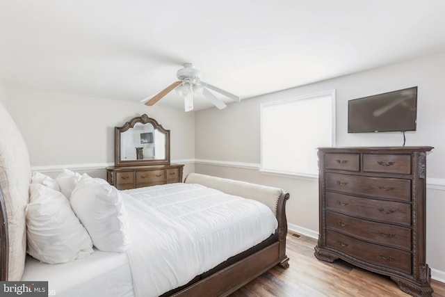 bedroom with light wood finished floors, baseboards, and ceiling fan