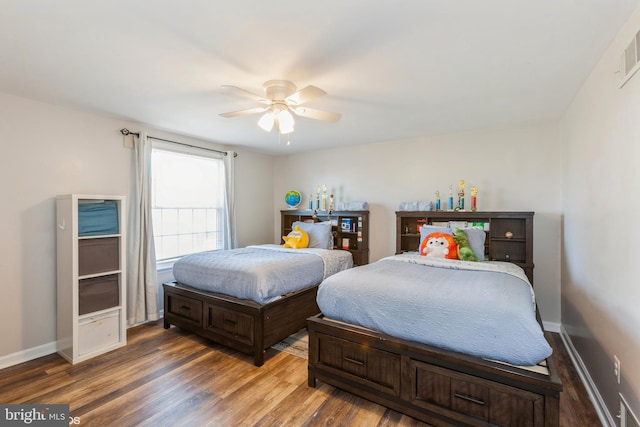 bedroom with a ceiling fan, wood finished floors, and baseboards