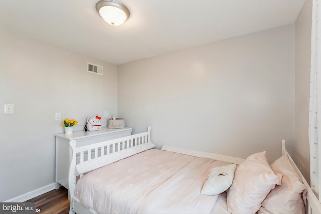 bedroom with visible vents, baseboards, and wood finished floors