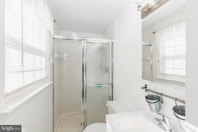 full bathroom featuring plenty of natural light, a stall shower, and toilet