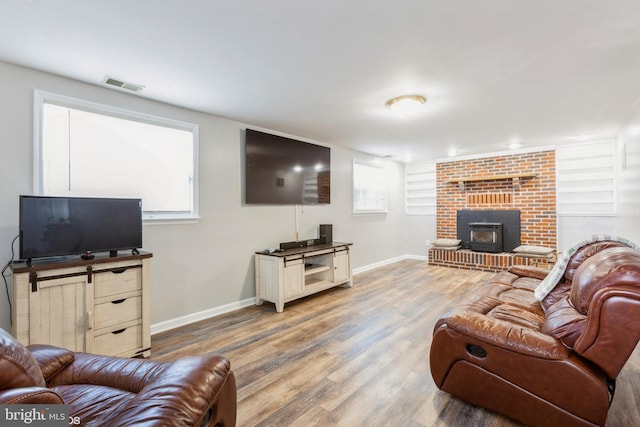 living area with visible vents, a wood stove, baseboards, and wood finished floors