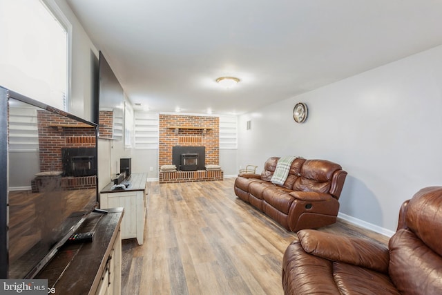 living room with light wood finished floors, a fireplace, and baseboards