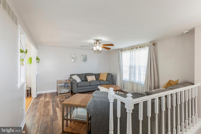 living room with a ceiling fan, visible vents, wood finished floors, and baseboards