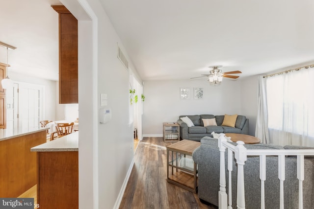 living room featuring ceiling fan, visible vents, dark wood-style flooring, and baseboards