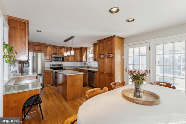 kitchen with a center island, light countertops, light wood-style flooring, appliances with stainless steel finishes, and brown cabinets