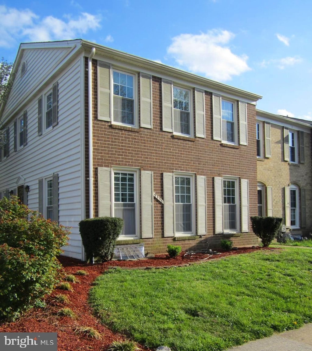 colonial home featuring brick siding and a front lawn