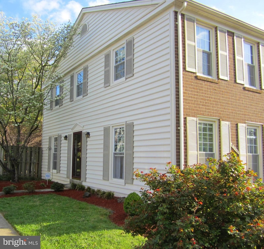 colonial house with brick siding, a front yard, and fence