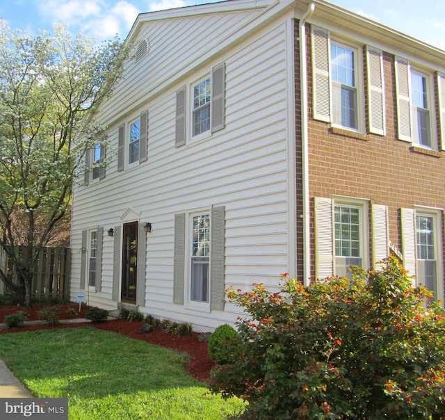 colonial house with brick siding, a front yard, and fence