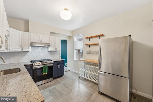 kitchen with a sink, under cabinet range hood, backsplash, white cabinetry, and stainless steel appliances