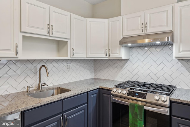 kitchen with stainless steel gas range oven, under cabinet range hood, decorative backsplash, white cabinetry, and a sink