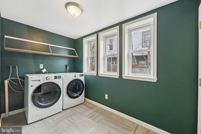 clothes washing area featuring laundry area, washer and dryer, and baseboards