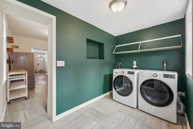 laundry area with washing machine and clothes dryer, laundry area, visible vents, and baseboards