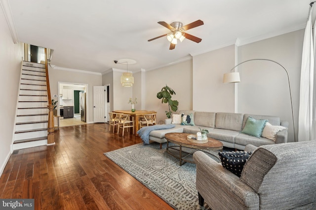 living area featuring stairway, wood-type flooring, ornamental molding, and a ceiling fan