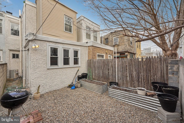 rear view of house with stucco siding and fence