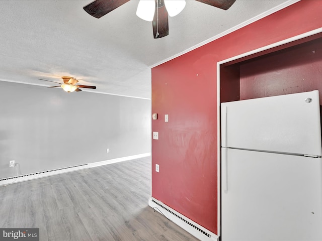 kitchen featuring a textured ceiling, baseboard heating, wood finished floors, and freestanding refrigerator