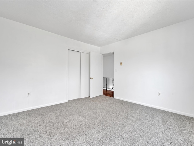 carpeted empty room with baseboards and a textured ceiling