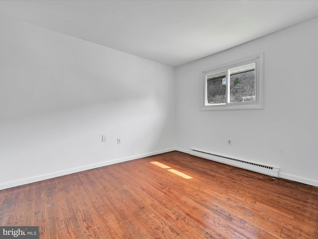 unfurnished room featuring a baseboard radiator, baseboards, and hardwood / wood-style flooring