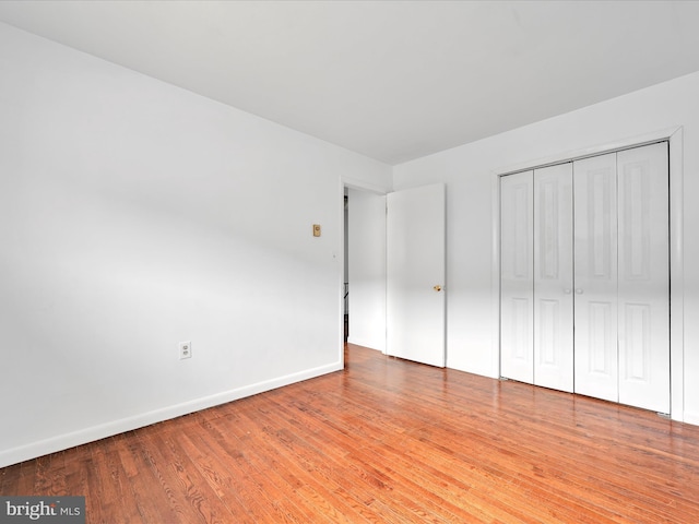 unfurnished bedroom with a closet, baseboards, and wood-type flooring