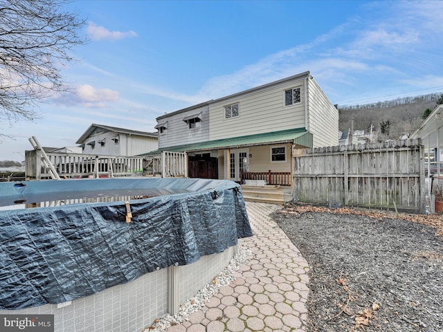 back of house featuring french doors, a deck, and fence