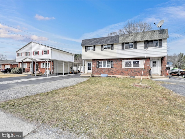 view of front of house with entry steps, a front lawn, brick siding, and roof with shingles