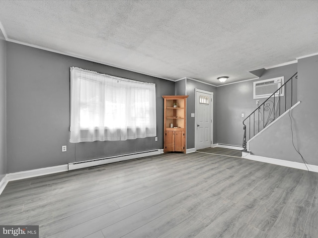 interior space featuring ornamental molding, a baseboard heating unit, wood finished floors, stairway, and baseboards