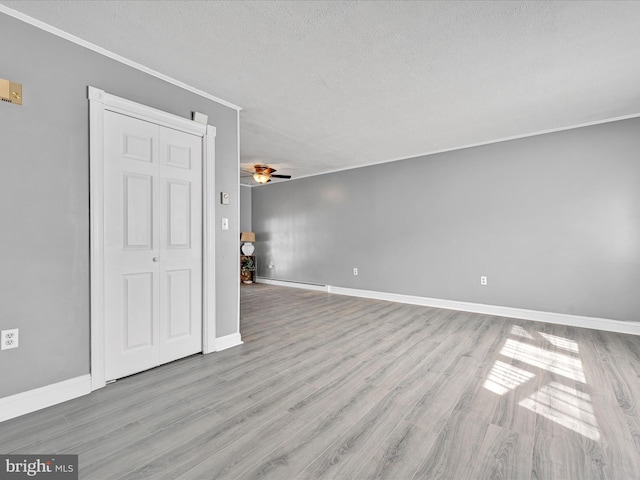 spare room with a baseboard heating unit, baseboards, ceiling fan, wood finished floors, and a textured ceiling