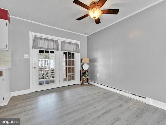 empty room featuring a ceiling fan, wood finished floors, baseboards, ornamental molding, and a baseboard heating unit