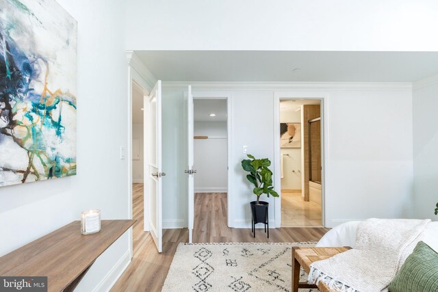 sitting room with light wood-type flooring, baseboards, and ornamental molding