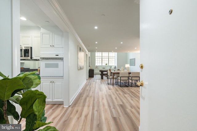 kitchen with recessed lighting, oven, white cabinets, light wood-style floors, and stainless steel microwave