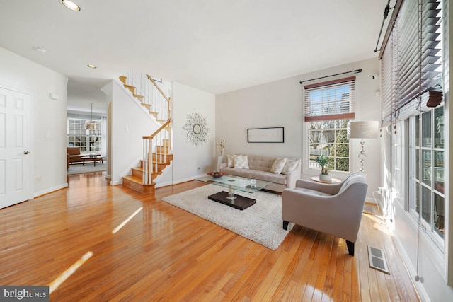 living area with hardwood / wood-style floors, stairway, baseboards, visible vents, and recessed lighting