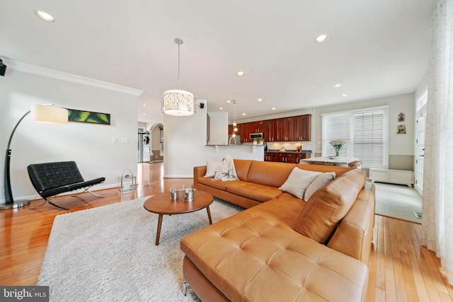 living area with recessed lighting, light wood-style floors, arched walkways, and baseboards