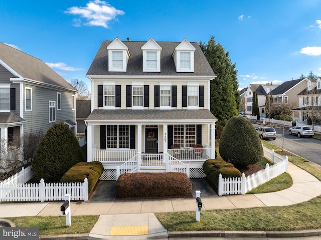 view of front of home featuring a fenced front yard, covered porch, and a shingled roof