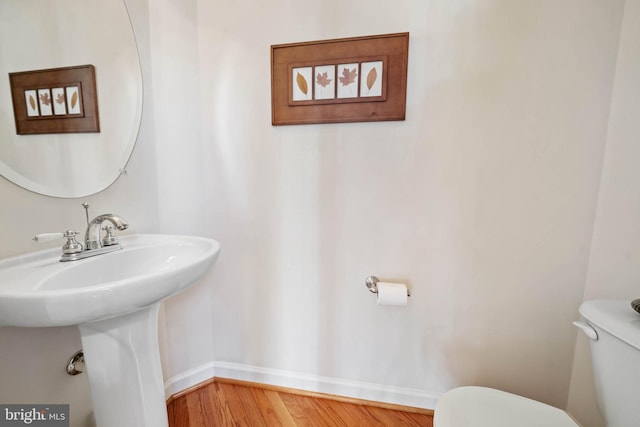 bathroom featuring toilet, wood finished floors, and baseboards