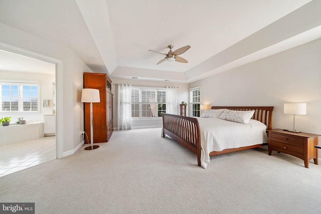 bedroom with tile patterned floors, a raised ceiling, ensuite bathroom, carpet floors, and baseboards