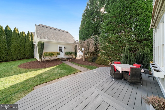 wooden deck with outdoor dining area, a lawn, and an outdoor structure