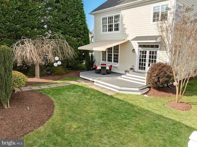 rear view of house with a shingled roof and a yard