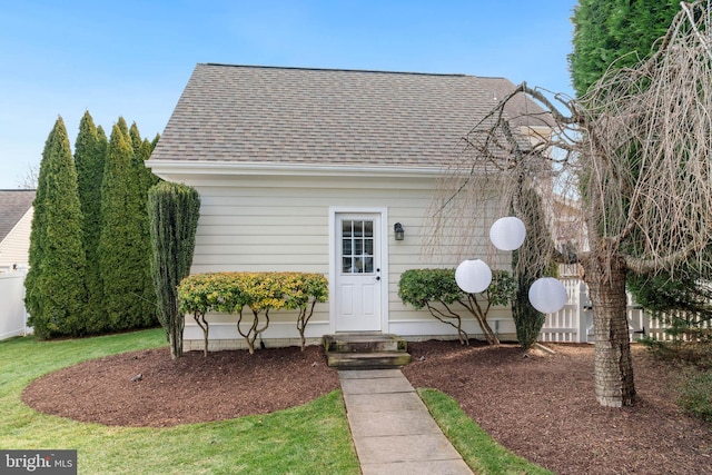 view of front facade featuring fence and a shingled roof