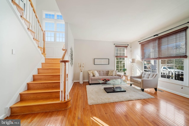 living area featuring stairs, hardwood / wood-style flooring, visible vents, and baseboards