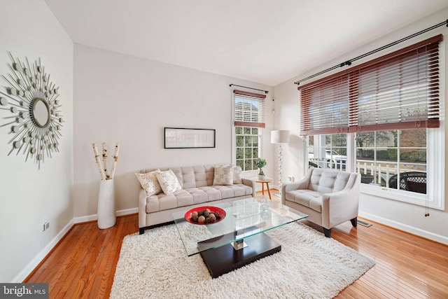 living area with hardwood / wood-style flooring, visible vents, and baseboards