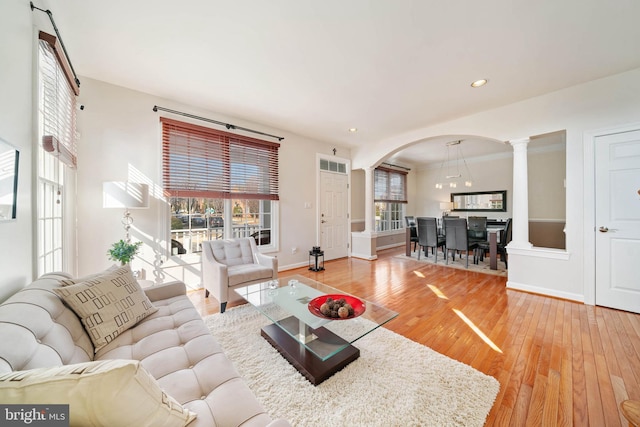 living room with hardwood / wood-style flooring, recessed lighting, arched walkways, decorative columns, and baseboards