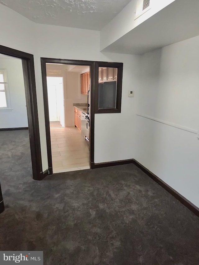 spare room with baseboards, visible vents, and dark carpet