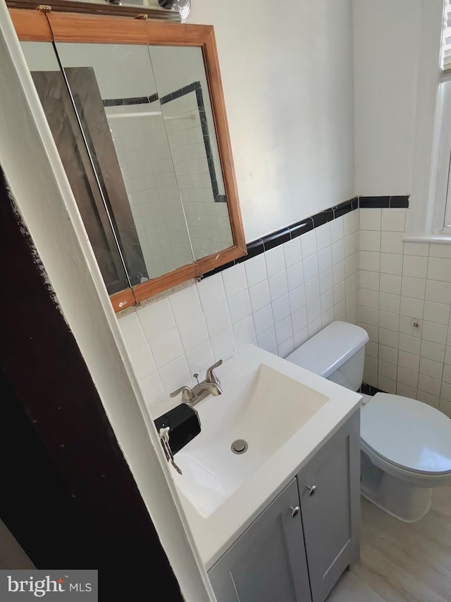 bathroom with tile walls, toilet, and vanity