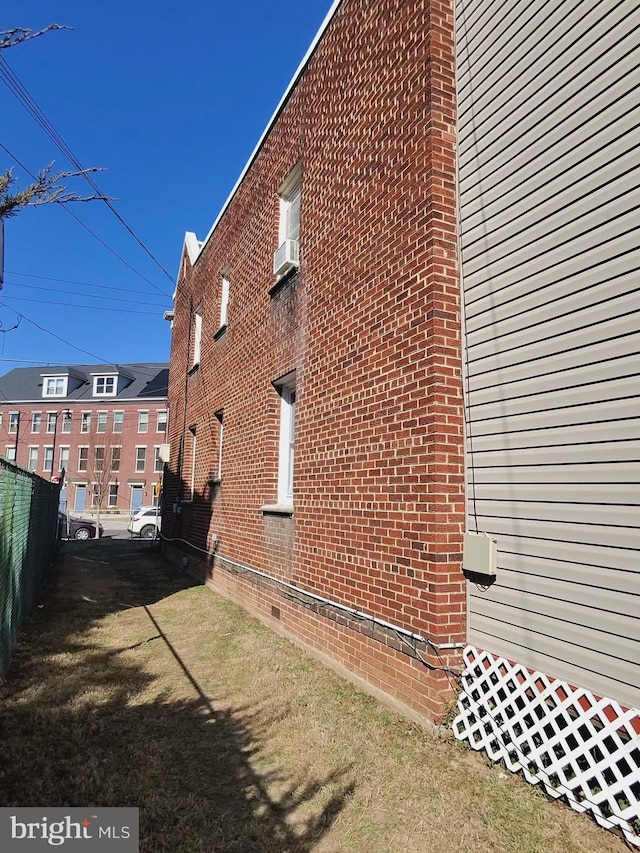 view of side of property featuring brick siding, a yard, and fence