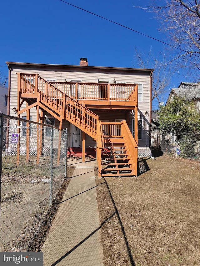 back of house with stairway, a chimney, a deck, and fence